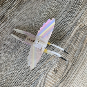 Detail view of bird-shaped acetate hair claw featuring marble texture and pearly finish