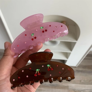 Detail of two resin hair claws with sparkling cherry rhinestone patterns in pink and brown