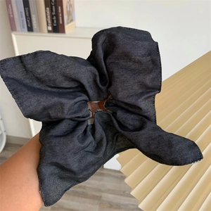 Macro shot of oversized black denim hair scrunchie with exaggerated pleats on wrist