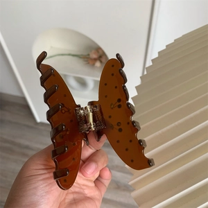 Detailed view of an amber butterfly hair claw clip with black dots and a strong spring