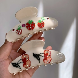 Close-up of cream hair claws with sparkling cherry and strawberry rhinestone motifs