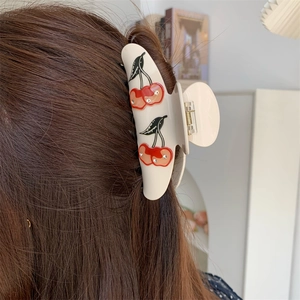 Detailed view of cream acetate hair claw clip with crystal cherry patterns on brown hair