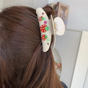 Detail of cream shark hair clip with strawberry pattern and rhinestones on hair