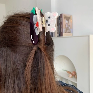 Détail d'une pince à cheveux créative en acétate avec ours et aubergine sur les cheveux