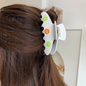 Pinza per capelli bianca con motivi a limone indossata su capelli castani