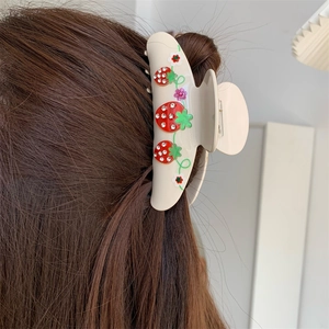 Detailed view of the red cherry pattern and sparkling rhinestones on the hair claw clip