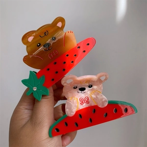 Détails d'une pince à cheveux en acétate avec ours mignon et motif de fruits colorés