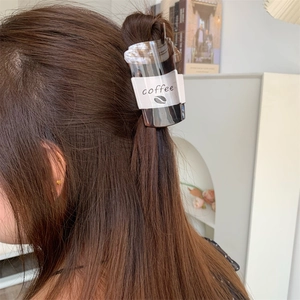 Detailed close-up of a creative coffee cup hair claw clip holding hair in a semi-tied style