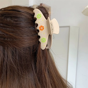 Dettaglio della molletta in acetato con motivo a limone e strass brillanti sulla clip