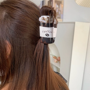 Detail of creative coffee cup shaped hair claw clip on model in a cozy indoor setting