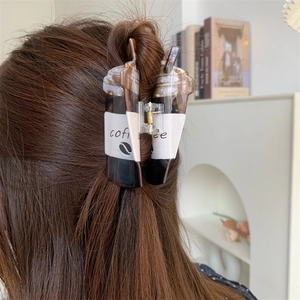 Close-up of creative coffee cup hair claw clip worn on long brown hair from the side