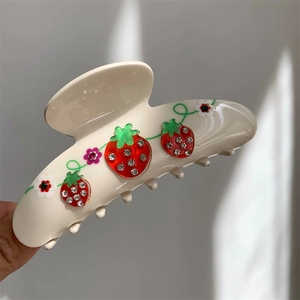 Close-up of cream hair claw clip with crystal cherry pattern and floral resin details