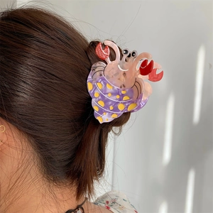 Détail d'une pince à cheveux crabe ermite créative rose portée sur cheveux bruns