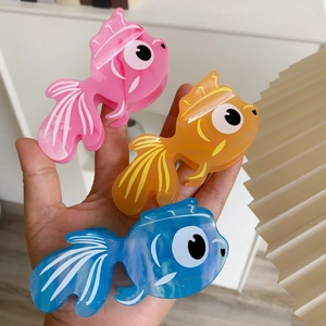 Vue détaillée des pinces à cheveux poisson rouge en acétate coloré aux reflets marbrés