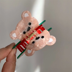 Détail de la pince à cheveux ours en acétate rose marbré avec dents rouges et ressort