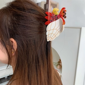 Detail der Haarklammer mit Einsiedlerkrebs-Design und Muschel auf braunem Haar