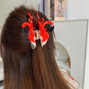 Pince à cheveux crabe à pois rouge, blanc et noir portée sur de longs cheveux