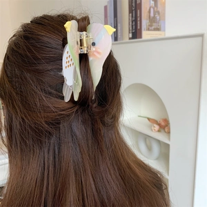 Detailed view of acetate cockatiel bird hair claw clip worn on dark brown hair