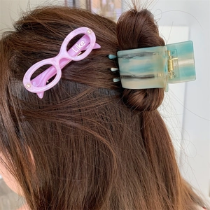 Detail of pink glasses hair clip with Like text and marble blue green hair claw