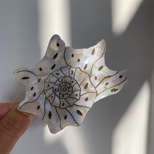 Close-up of a conch-shaped cream acetate hair claw with elegant black spiral textures