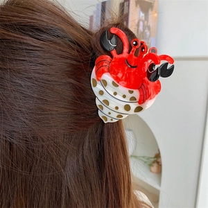 Détail de la pince à cheveux crabe rouge avec un design de coquillage à pois blancs