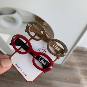 Detail view of acetate eyewear-shaped hair clips in red and brown with Like text