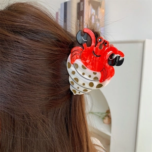 Détail d'une pince à cheveux crabe avec pois dorés portée sur cheveux châtains