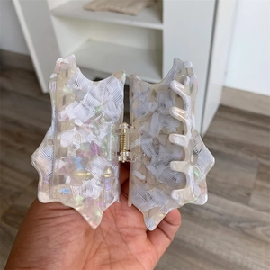 Close-up of white polka dot conch hair claw clip with iridescent pearlescent texture