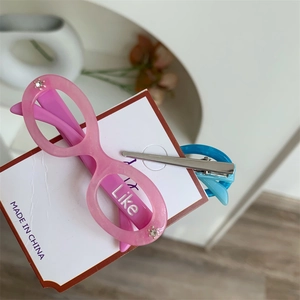 Detail of pink and blue glasses-shaped hair clips with crystals and Like letters