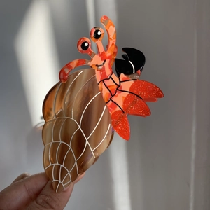 Makro-Detail einer Haarklammer aus Acetat in Einsiedlerkrebs-Form mit glänzender Oberfläche