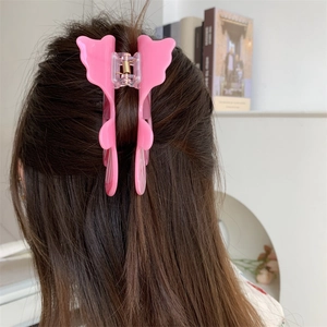 Pince à cheveux papillon rose portée sur de longs cheveux bruns dans un cadre chaleureux