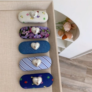 Détail de cinq pinces à cheveux en tissu fleuri avec boucles H argentées en forme de cœur