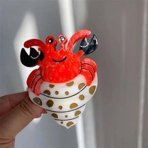 Détail d'une pince à cheveux créative en forme de crabe et coquillage à pois colorés