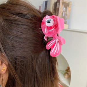 Détail d'une pince à cheveux poisson rouge rose avec texture marbrée sur les cheveux