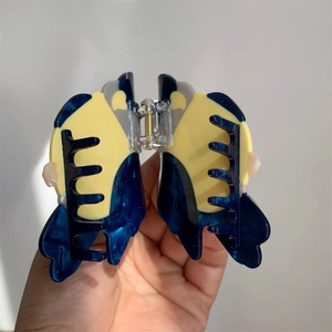 Detailed view of bird-shaped acetate hair claw with marble texture and gold metal spring