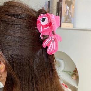 Détail de la pince à cheveux poisson rouge rose avec texture marbrée sur un modèle