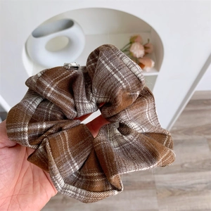 Close-up of retro brown plaid scrunchie fabric with a silver rhinestone metal detail