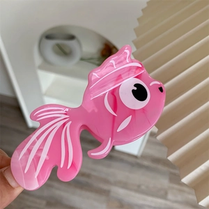 Vue détaillée d'une pince à cheveux en forme de poisson rouge avec texture marbrée rose
