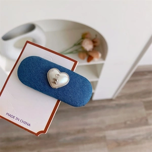 Détail macro de la pince à cheveux en denim bleu avec incrustation en forme de cœur argenté