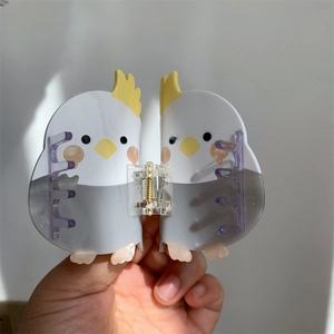 Detail of cute bird-shaped hair claw clip with colorful cockatiel design and golden spring