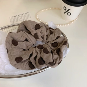 Haargummi mit Polka-Dots aus braunem Stoff in einem Metallkorb für Vintage-Dekoration