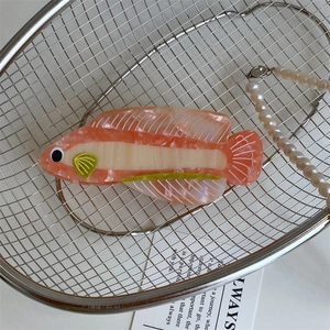 Dettaglio macro della pinza per capelli in acetato a forma di pesce rosa marmorizzato