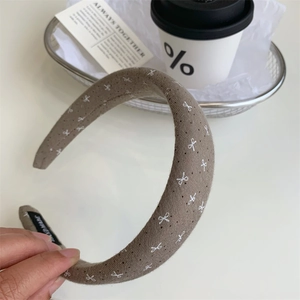 Detailansicht des handgefertigten braunen Stirnbands mit weißen Schleifen und Punkten
