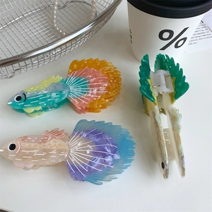 Dettaglio macro di fermagli per capelli in acetato a forma di pesce con sfumatura perlata