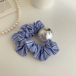Détail d'un chouchou en tissu rayé bleu avec breloque boule argentée et gravure OFF