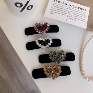 Dettaglio del set di quattro fermagli per capelli a cuore con strass su base di velluto nero