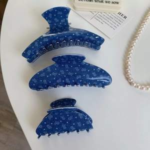 Detailed set of three blue star and heart print hair claws in various sizes on a table