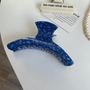 Detailed view of blue denim pattern hair claw clip with star and heart prints for styling