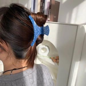 Navy blue star print hair claw clip worn by a model in a cozy indoor setting