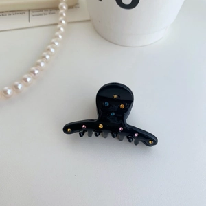 Dettaglio del fermaglio per capelli in acetato nero con strass colorati e vivaci